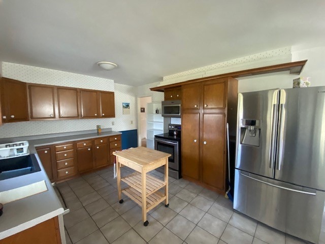 kitchen with stainless steel appliances, light tile patterned flooring, and sink