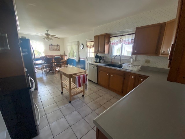 kitchen with light tile patterned flooring, ceiling fan, refrigerator, sink, and dishwasher