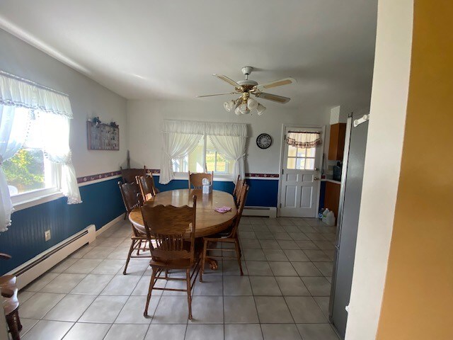 tiled dining room featuring ceiling fan and baseboard heating