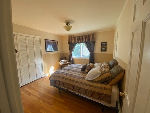 bedroom with a closet, crown molding, and light hardwood / wood-style floors