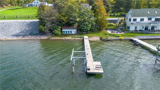 dock area with a water view, a yard, and a balcony