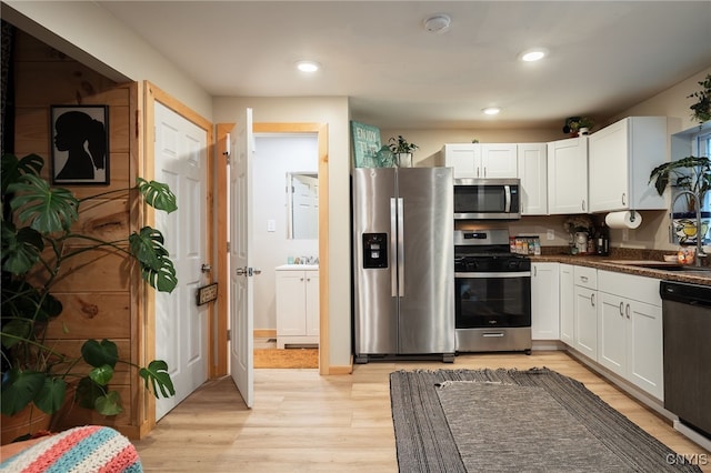 kitchen featuring stainless steel appliances, white cabinetry, light wood-type flooring, and sink