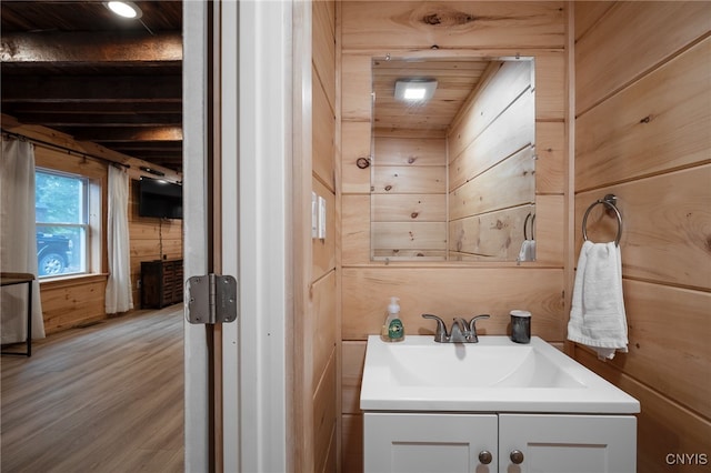 bathroom with wood-type flooring, wood walls, and vanity