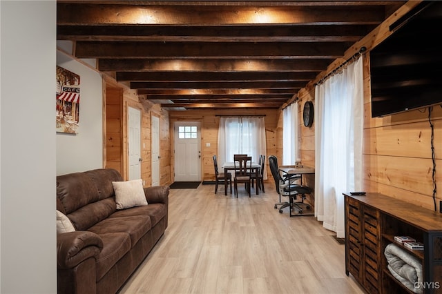 living room with beamed ceiling, wood walls, and light hardwood / wood-style flooring