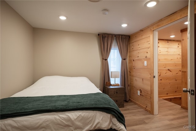 bedroom featuring wooden walls and hardwood / wood-style floors