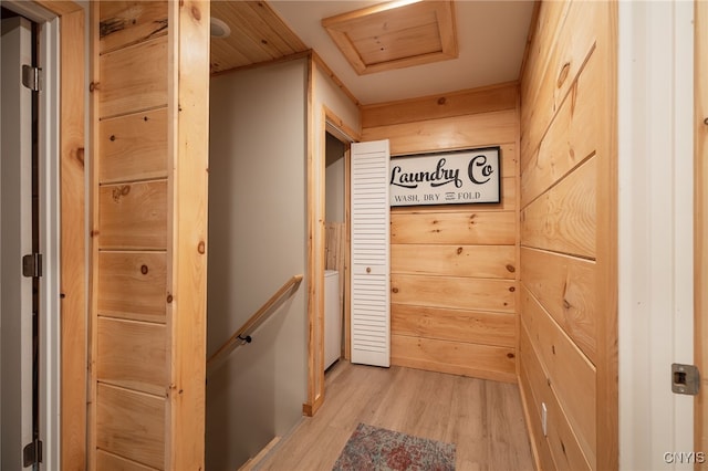 hall featuring light hardwood / wood-style floors and wooden walls