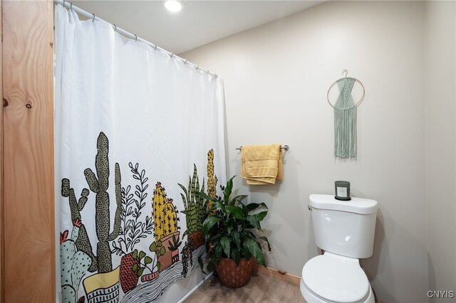 bathroom featuring hardwood / wood-style floors, toilet, and a shower with shower curtain