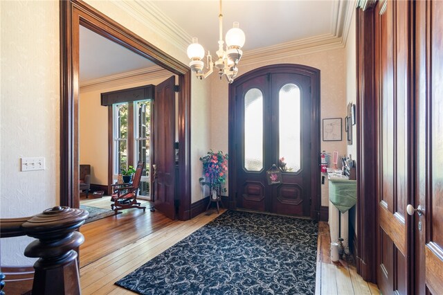 foyer entrance with ornamental molding, an inviting chandelier, and light hardwood / wood-style floors