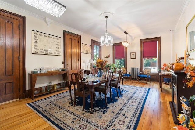 dining area featuring ornamental molding, radiator, a notable chandelier, and light wood-style floors