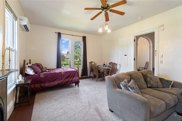 bedroom with ceiling fan, a wall mounted air conditioner, and carpet