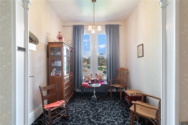 living area featuring a chandelier, decorative columns, and carpet flooring