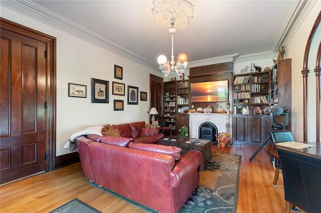 living room featuring a fireplace, crown molding, a chandelier, and wood finished floors