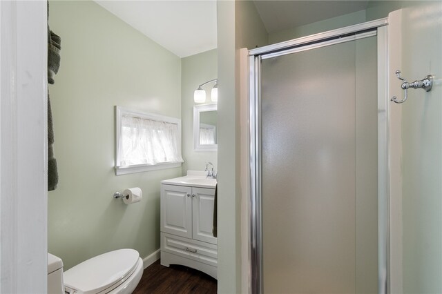 bathroom with hardwood / wood-style floors, a shower with door, vanity, and toilet