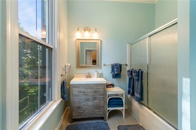 bathroom with shower / bath combination with glass door, vanity, and plenty of natural light