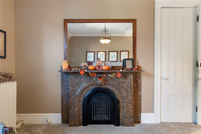 room details with a fireplace with flush hearth, crown molding, radiator heating unit, and carpet