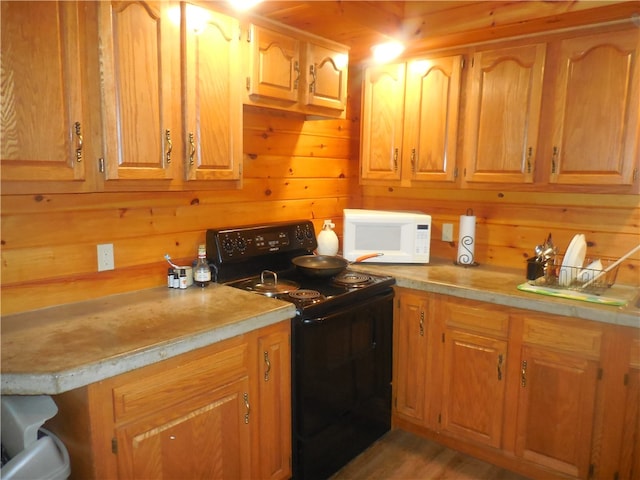 kitchen featuring light hardwood / wood-style flooring, wood walls, and black electric range