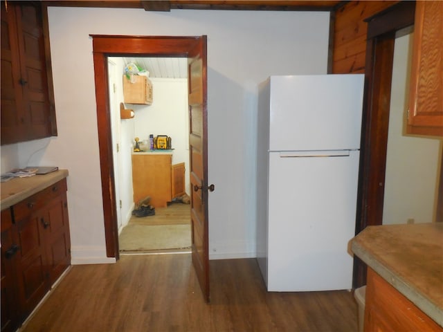 kitchen featuring hardwood / wood-style flooring, wooden walls, and white fridge