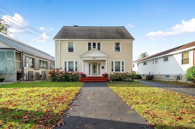 view of front of home with cooling unit and a front lawn