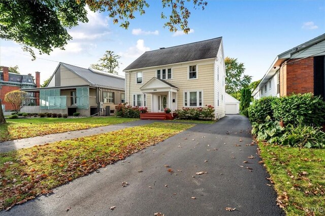 view of front of house featuring a garage, an outdoor structure, and a front lawn