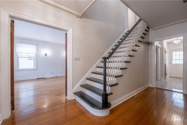 stairway with wood-type flooring, a wealth of natural light, and crown molding