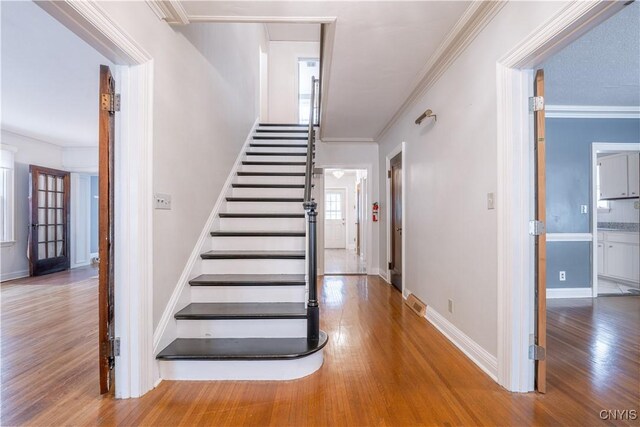 stairway featuring crown molding and hardwood / wood-style floors