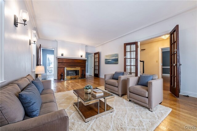 living room with light wood-type flooring, french doors, and ornamental molding