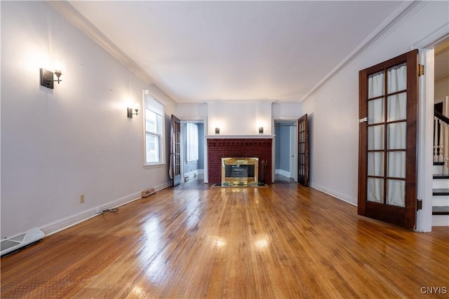 unfurnished living room featuring wood-type flooring, ornamental molding, and a fireplace