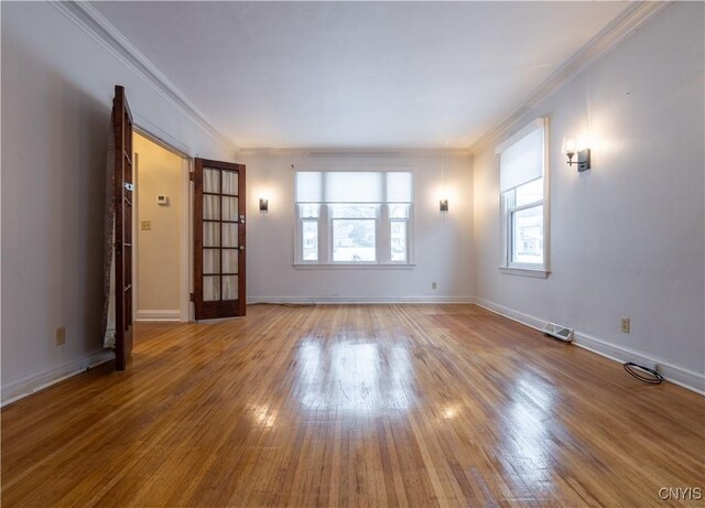 empty room with crown molding, a healthy amount of sunlight, and wood-type flooring