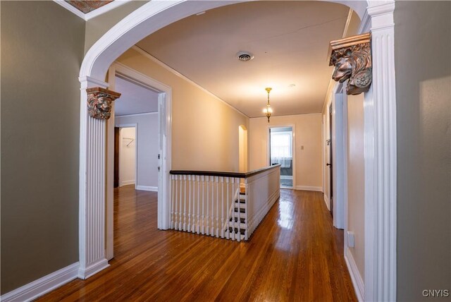 hall with dark hardwood / wood-style floors, ornamental molding, and decorative columns