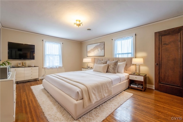 bedroom featuring dark hardwood / wood-style flooring, multiple windows, and ornamental molding