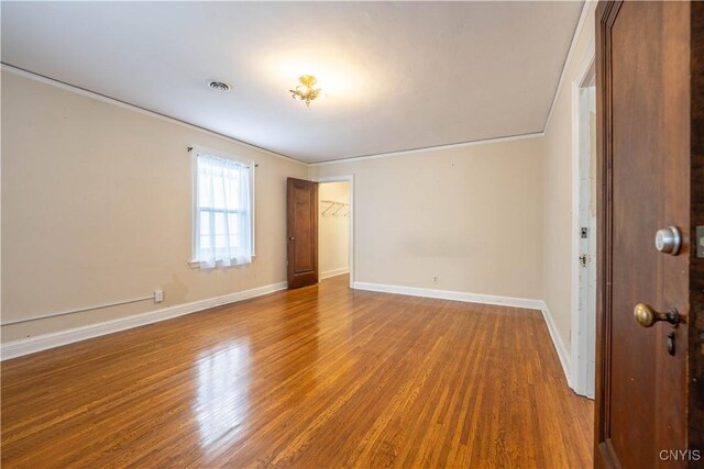 empty room with hardwood / wood-style floors and crown molding