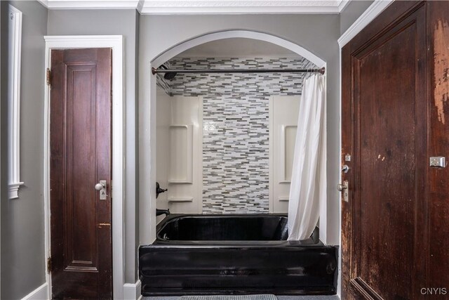 bathroom with decorative backsplash, crown molding, and shower / bathtub combination with curtain