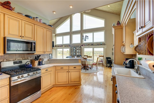 kitchen featuring stainless steel appliances, sink, high vaulted ceiling, and light hardwood / wood-style flooring