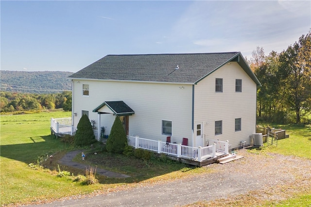 view of side of property featuring a lawn, a deck, and central air condition unit