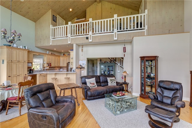 living room featuring a notable chandelier, light hardwood / wood-style flooring, and high vaulted ceiling