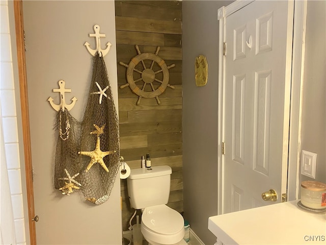 bathroom featuring wood walls, vanity, and toilet