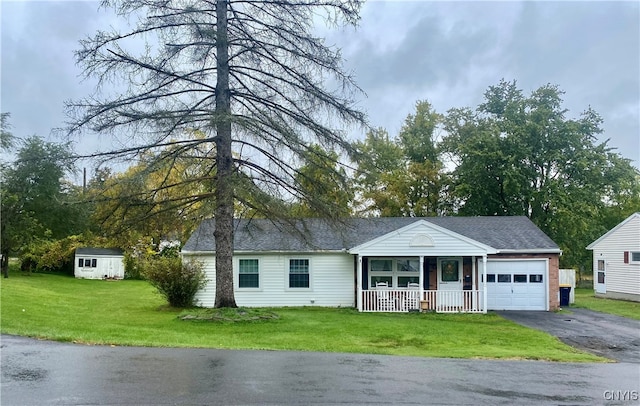 single story home with a storage shed, a porch, a garage, and a front yard