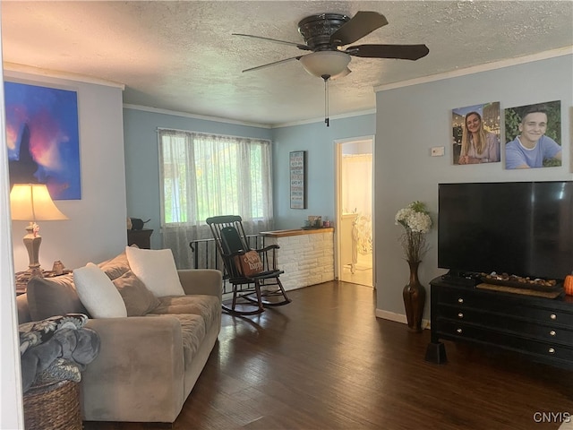 living room featuring ornamental molding, ceiling fan, a textured ceiling, and dark wood-type flooring