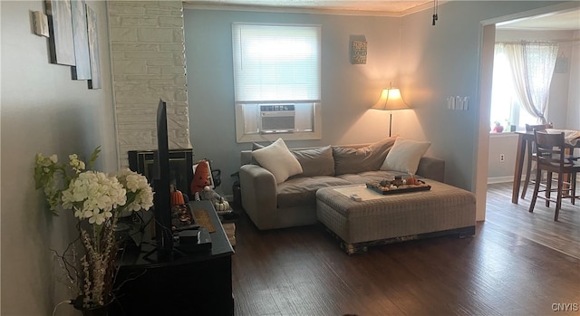 living room with ornamental molding, cooling unit, dark hardwood / wood-style floors, and a stone fireplace