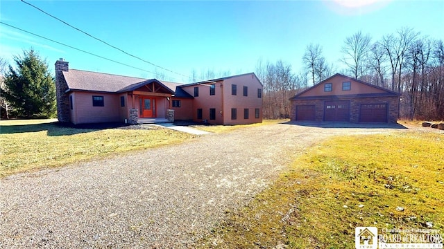 view of front facade with a front yard, a garage, and an outbuilding