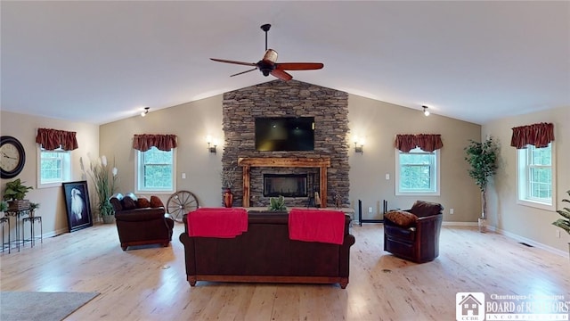 living room featuring a wealth of natural light, lofted ceiling, a fireplace, and light wood-type flooring