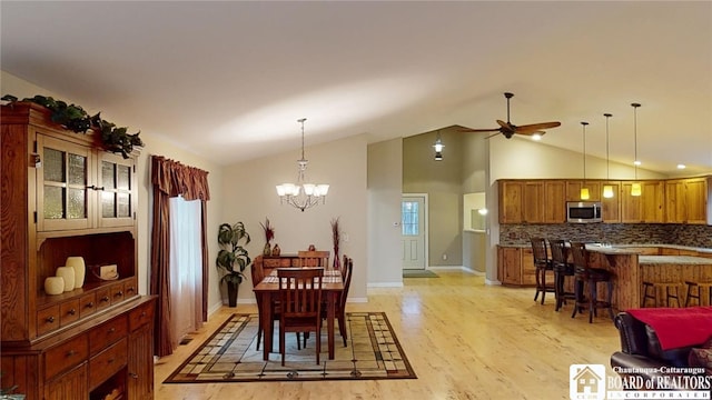 dining room featuring ceiling fan with notable chandelier, lofted ceiling, light hardwood / wood-style flooring, and plenty of natural light