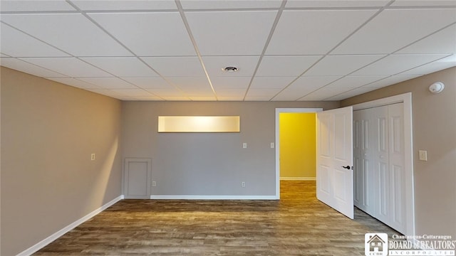 unfurnished room featuring wood-type flooring and a drop ceiling