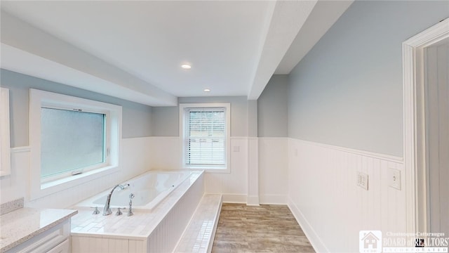 bathroom with tiled tub, vanity, and hardwood / wood-style flooring