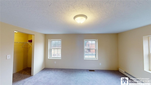 unfurnished bedroom featuring carpet floors, a textured ceiling, a closet, and a spacious closet