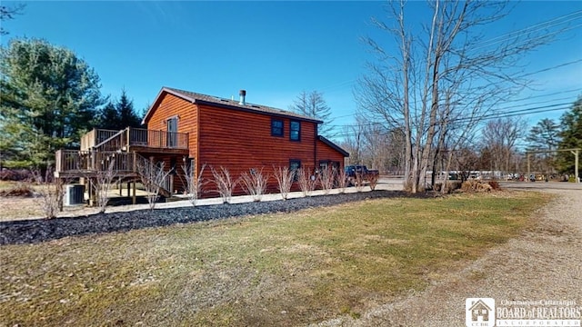 view of side of property with a wooden deck, central AC, and a yard