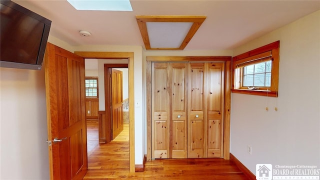 hallway featuring light wood-type flooring and a skylight