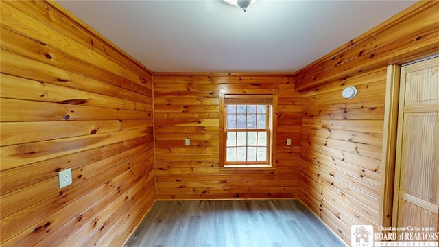 spare room featuring wood-type flooring and wooden walls