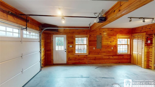 garage featuring a garage door opener, wood walls, and electric panel