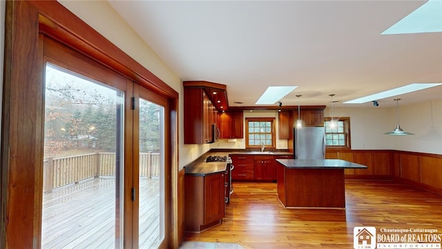 kitchen with pendant lighting, a skylight, appliances with stainless steel finishes, and a healthy amount of sunlight